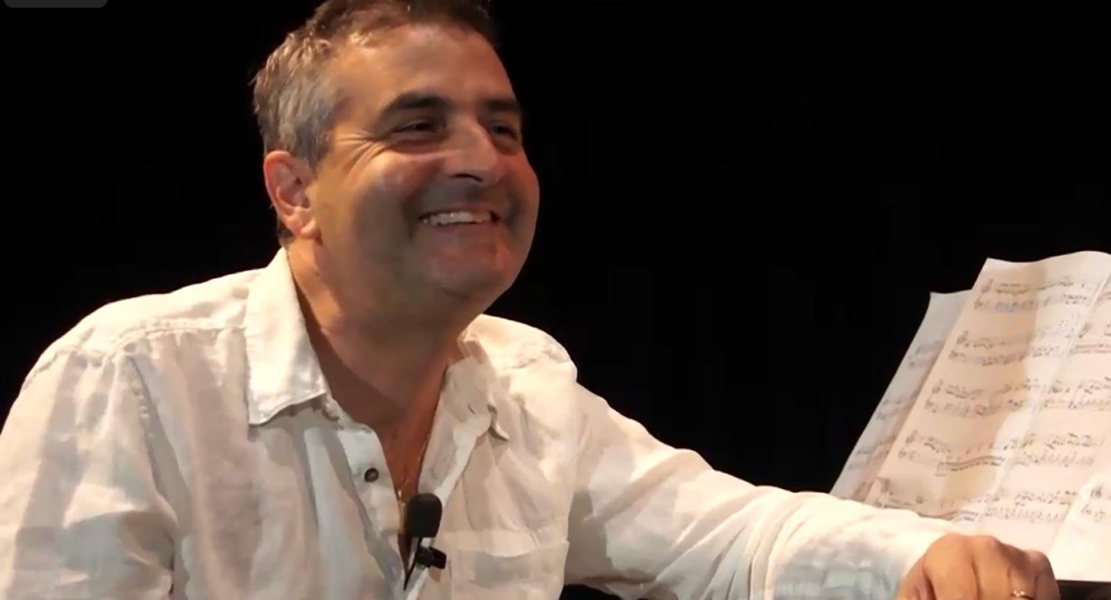 Claude Tedesco souriant au piano, partition ouverte